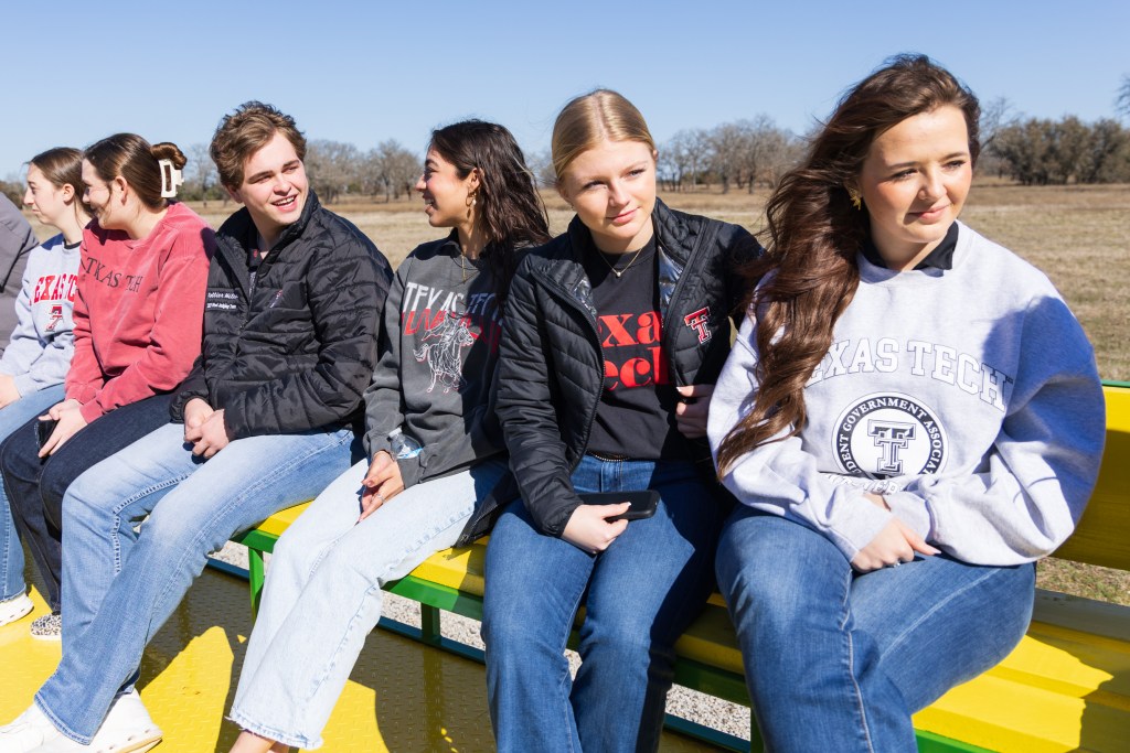 A group of students from the MILE Program sitting on a colorful bench at the Wood Ranch during their retreat, engaging with each other in a sunny outdoor setting.