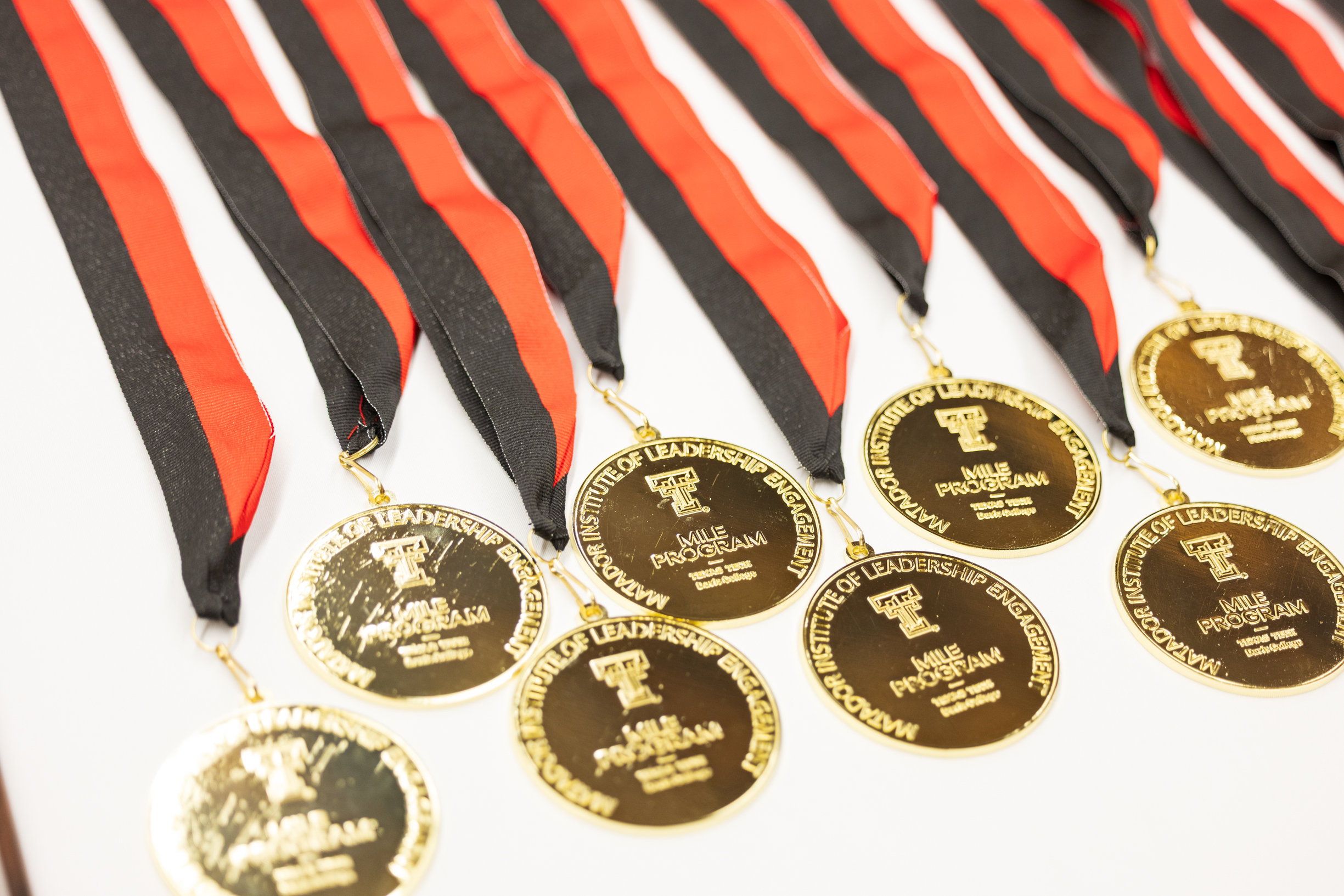 A collection of gold medals with red and black ribbons lay on a white table.